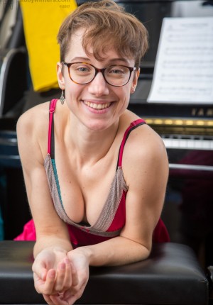 Nerdy glasses wearing Gretchen plays with her pussy fur at the piano