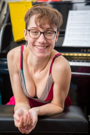 Nerdy glasses wearing Gretchen plays with her pussy fur at the piano
